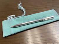 Top view of pen resting on Tiffany blue pouch, showing engraved body and pouch branding