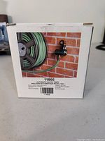 Box of automatic water timer showing product attached to faucet and garden hose reel.