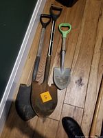 Photo showing two metal shovels with D-grip handles and a kids shovel with green handle.