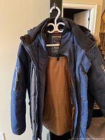 Full front view of navy blue winter coat with zipper open showing brown quilted lining and fur-trimmed hood