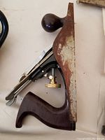 Top-down photo showing two woodworking planes: one metal Stanley with adjustable brass knob and one wooden-bodied plane with dark handle and knob. Both show signs of use and surface wear.