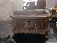 Front angle showing the ornate keyhole and detailed floral scrolls on the bronze coffer box.