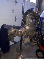 Side view of the carousel horse showing detailed saddle, harness, metallic paint, mounted on brass pole with wool tail