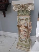 Side view of the pedestal showing sculpted cupids and intricate floral designs on rectangular body