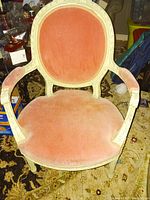 Front view of Louis XIV style chair showing rose pink velvet seat and oval back with carved cream painted wooden frame