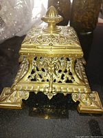 Top front angle view showing detailed brass openwork and finial on lid