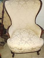 Front view showing beige floral upholstery and wooden frame with carved detail.