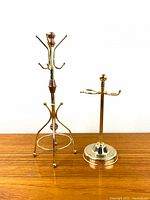Full view of both brass display stands side by side on wooden surface against white background, showing size and design.