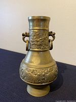 Front view of brass urn showing overall shape and relief designs