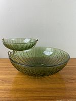 Front view showing large textured avocado green bowl with smaller bowl held above by brass bracket.