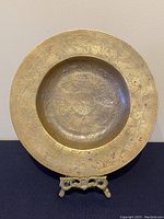 Full view of brass display plate with dragon and floral engravings on a stand, showcasing the entire plate.