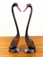 Pair of cast metal bird figurines with etched design and red painted beaks and body highlights, standing tall side by side.