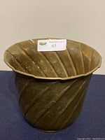 Full view of the brass planter showing swirl pattern and scalloped rim.