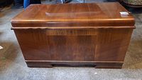 Front view of the closed cedar-lined wooden chest, showing polished veneer and keyhole.
