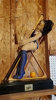 Full image of the figurine display showing the woman in blue stockings embracing billiard cues inside a triangle rack on a wooden base