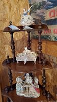 Three porcelain figurines arranged on a wooden display shelf, showing scale and condition