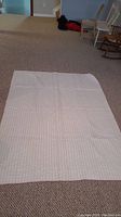 Full view of the laid out vintage quilt showing the white back side with faint grid lines and pink border visible from underneath.