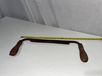 Front angled view showing wooden handles and metal blade, with tape measure visible for scale.
