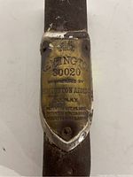 Close-up photo of the brass identification plate affixed to a metal rifle part, showing Remington 30020 model and patent details.