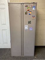 Front view of closed steel storage cabinet with magnets on door and lock at top center.