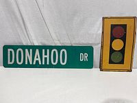 Donahoo Dr green metal street sign and yellow steel stoplight wall hanger on white backdrop