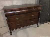 Front view of antique chest of drawers showing curved drawer fronts and claw feet with wheels.