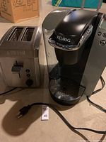 Side-by-side view of the Keurig coffee maker and Chef's stainless steel toaster showing power cords and overall condition.