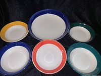 Overview of all six pasta bowls arranged on black background, showing different colored rims and white centers