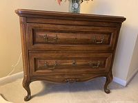 Front view showing two drawers with metal pulls, carved medallion on apron, and cabriole legs.