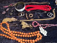 Full assortment of vintage costume jewelry laid out on black velvet, showing multiple necklaces, bracelets, earrings and a brooch with various bead and metal details.