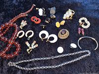 Full overview of the lot showing varied vintage jewelry pieces on dark velvet background.