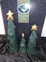 Photo of three carved wood Christmas trees with green layers and gold stars in front of original Williraye Studio box