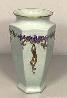 Front view of hexagonal porcelain vase showing purple flowers and gold rim.