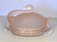Front view of the closed swan-shaped pink Rosalin glass butter dish showing the shape and frosted satin finish.
