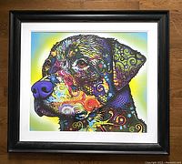 Framed colorful Rottweiler art print by Dean Russo shown front view on wooden surface.