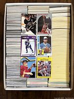 Box filled with thousands of assorted sports trading cards including hockey, baseball, basketball, and football cards; packed neatly.