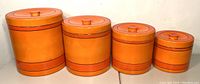 Four orange nesting canisters arranged in size order from largest to smallest, showing full set and colors