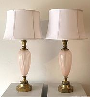 Pair of vintage table lamps with pink glass bodies and brass bases, white shades on top.