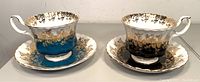 Pair of vintage Royal Albert Regal Series tea cups and saucers, one set blue and gold, one set black and gold