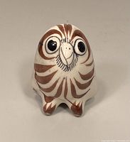 Front view of owl showing hand-painted brown and black facial patterns on a white ceramic base.