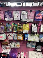Photo of assorted facial masks on pink slat wall display showing various brands and colorful packaging including Smile Age, Anself, and Wutt.