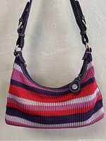 Front view of knitted striped handbag with leather strap and logo charm