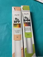 Photo shows two boxed cosmetic tubes: one labeled My BFF Matte Concealer in Light shade, the other My B4N Green Color Corrector by Amor Us.