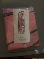 Photo showing the pink Boutique flag folded and packaged in plastic with label SF-X27 and size 3x5 ft.