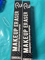 Photo showing two boxed Makeup Eraser products side by side on a turquoise surface.