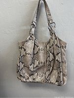 Front view of snake print large handbag hanging on wall.