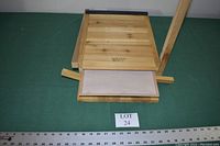 Top-down angled photo of the cedar bat house showing the closed wooden panels and mounting wings extending sideways. A ruler is placed below the item for scale.