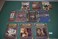 All ten books and Dungeon Master's screen displayed on green felt surface