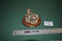 Photo of two otters sculpture on wooden oval base with measuring ruler showing dimensions and lot number 18