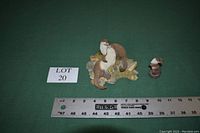 Photo showing two small otter sculptures on a green background alongside a ruler for size reference.
